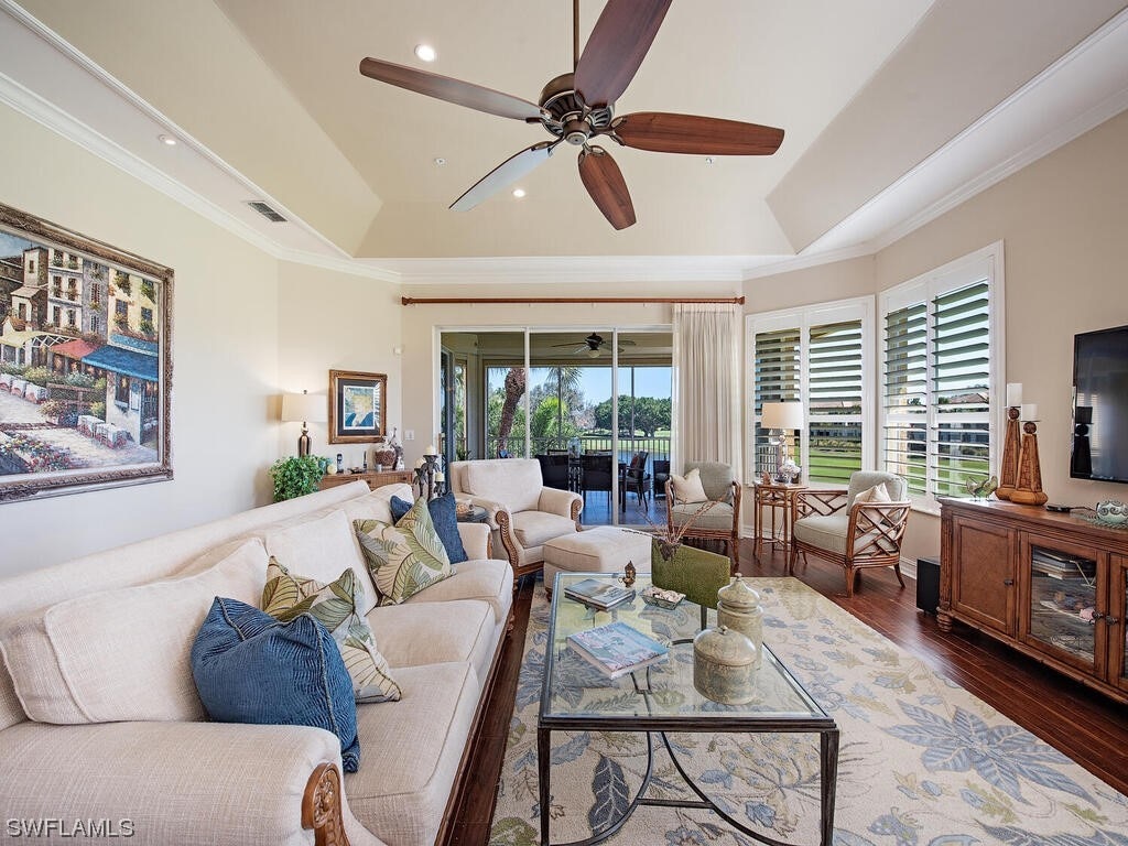 living room with a tray ceiling, a wealth of natural light, dark hardwood / wood-style floors, and ceiling fan