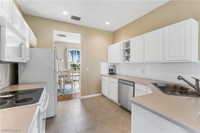 kitchen with tasteful backsplash, white appliances, white cabinets, and sink