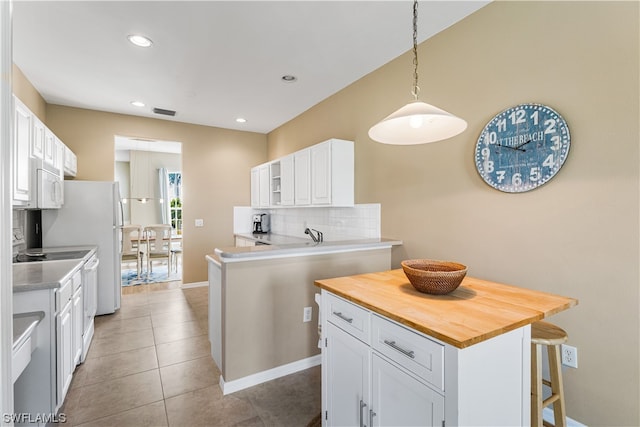 kitchen with white appliances, white cabinets, backsplash, and pendant lighting