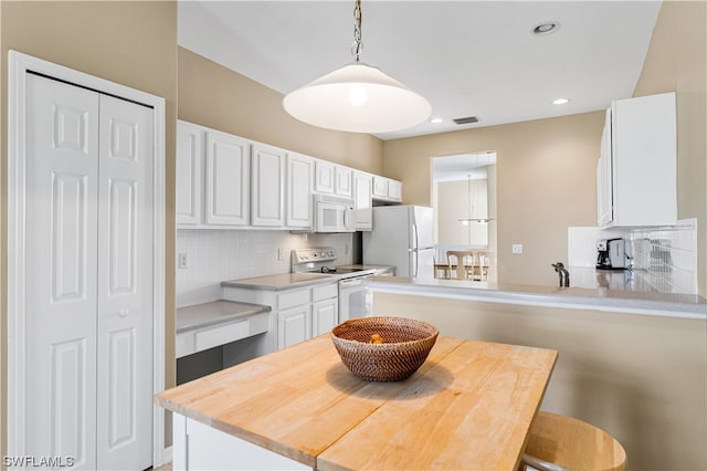 kitchen with white cabinetry, backsplash, white appliances, a kitchen breakfast bar, and pendant lighting