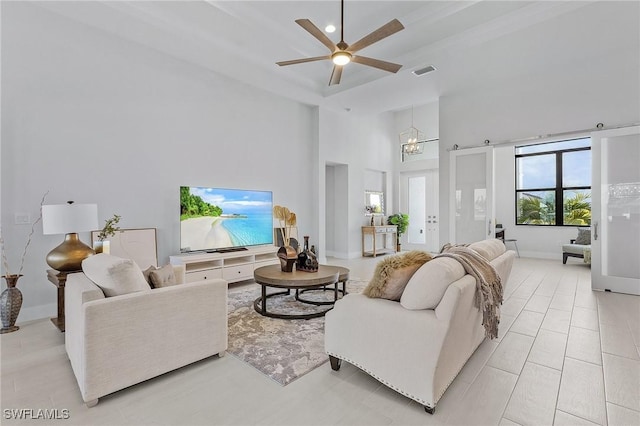 living room featuring a towering ceiling and ceiling fan with notable chandelier