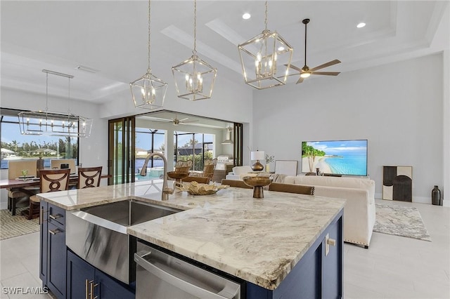 kitchen with a center island with sink, blue cabinets, stainless steel dishwasher, ceiling fan, and decorative light fixtures