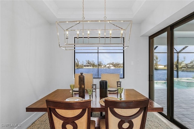 dining room featuring a water view, a wealth of natural light, and a tray ceiling