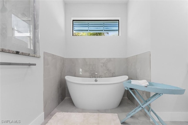 bathroom with a tub, tile patterned flooring, and tile walls