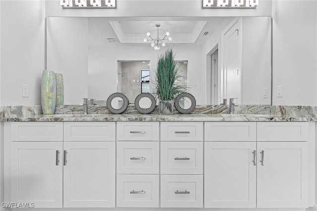 bathroom with a chandelier, vanity, a tray ceiling, and ornamental molding