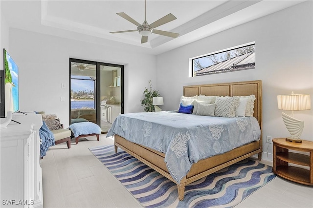 bedroom featuring access to outside, ceiling fan, a tray ceiling, and light hardwood / wood-style floors