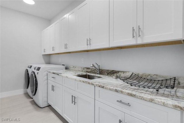 laundry area with washing machine and clothes dryer, sink, and cabinets