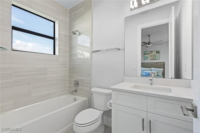 full bathroom featuring tiled shower / bath combo, ceiling fan, toilet, and vanity