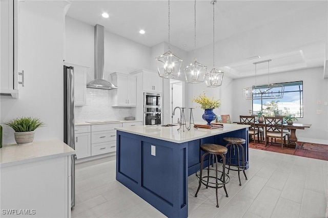 kitchen with pendant lighting, white cabinetry, stainless steel appliances, and a kitchen island with sink