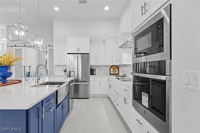 kitchen with blue cabinetry, white cabinetry, stainless steel appliances, pendant lighting, and decorative backsplash