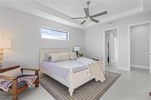 bedroom featuring a tray ceiling, ceiling fan, and light hardwood / wood-style floors