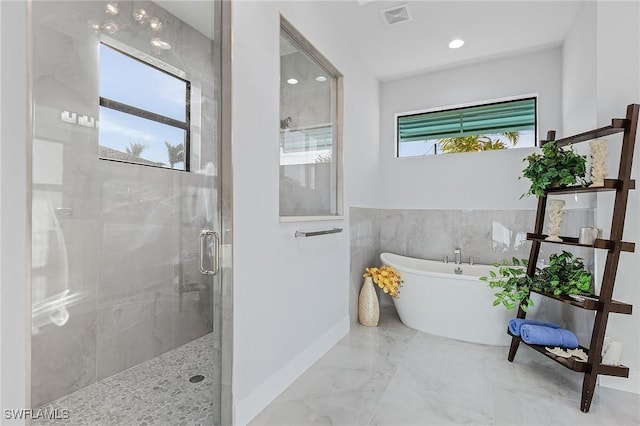 bathroom featuring plenty of natural light and independent shower and bath