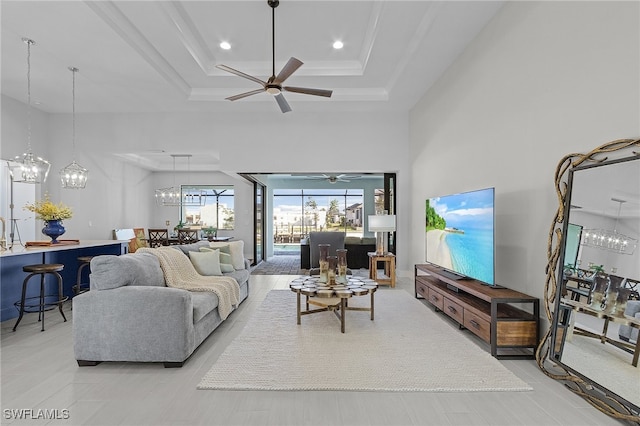 living room with ceiling fan, a high ceiling, and a tray ceiling