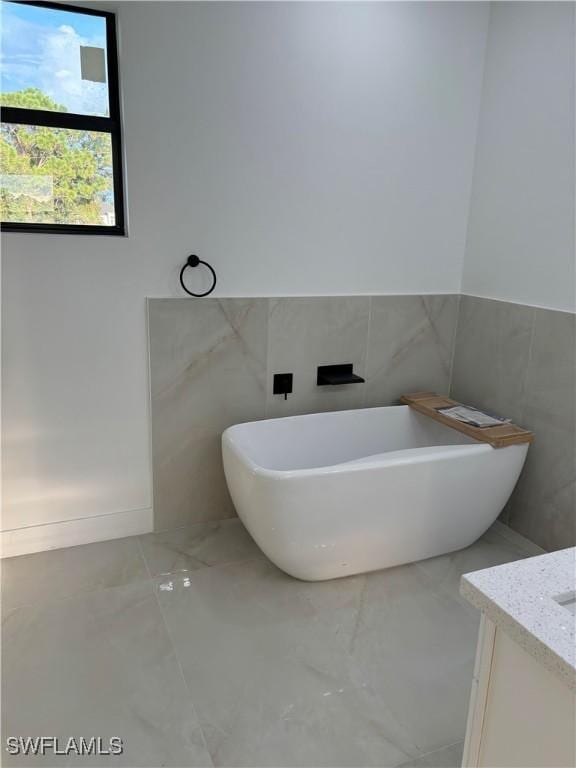 bathroom with vanity, a tub to relax in, and tile walls