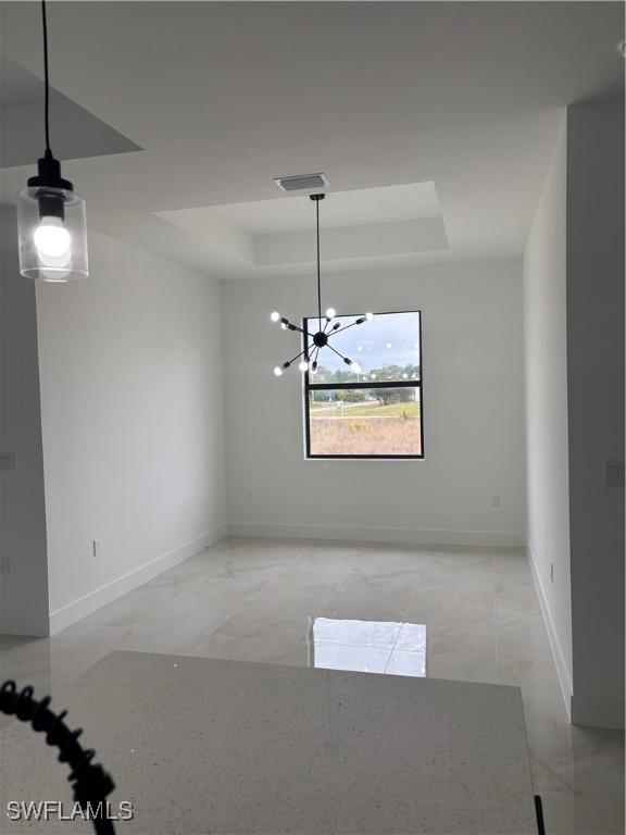 unfurnished room with a raised ceiling and a chandelier