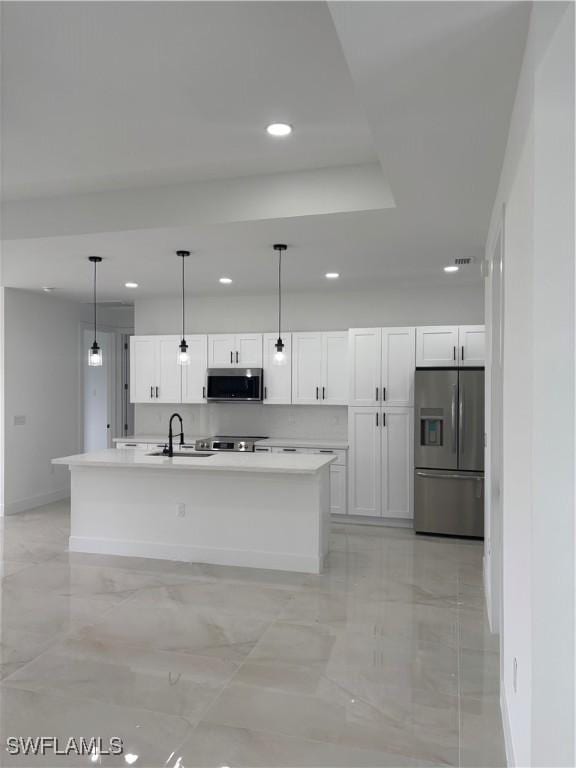 kitchen with sink, a center island with sink, appliances with stainless steel finishes, pendant lighting, and white cabinets