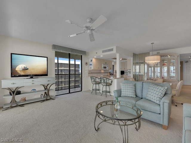 living room with light carpet and ceiling fan with notable chandelier