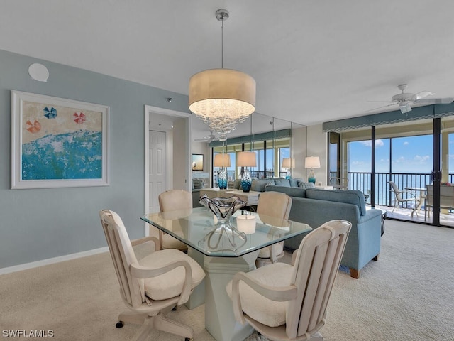 dining area featuring ceiling fan with notable chandelier and light colored carpet