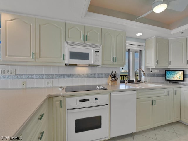 kitchen with ceiling fan, white appliances, backsplash, a raised ceiling, and sink