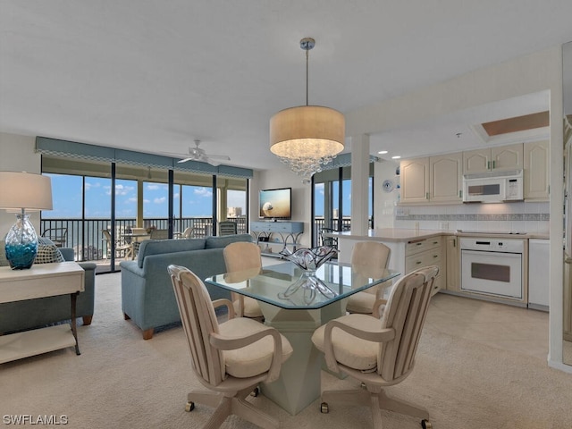 dining area with light carpet and ceiling fan with notable chandelier