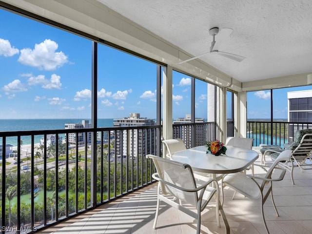 sunroom / solarium featuring a water view and ceiling fan