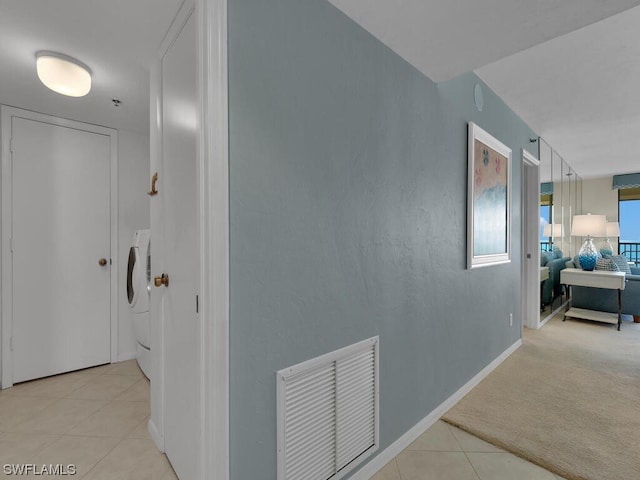 hall with washer / clothes dryer and light tile flooring