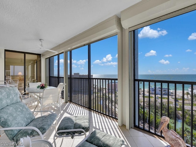 sunroom / solarium with ceiling fan and a water view