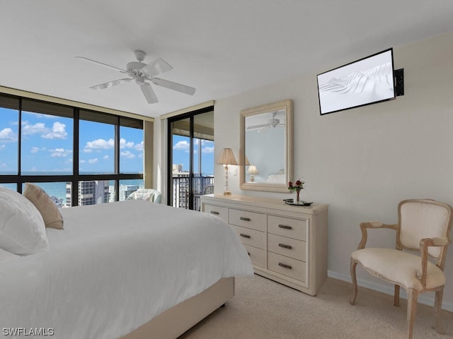 bedroom featuring ceiling fan, a wall of windows, light carpet, a water view, and access to outside