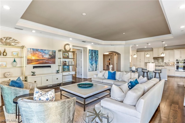 living room featuring wood-type flooring, crown molding, and a tray ceiling