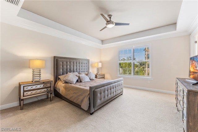 carpeted bedroom with a tray ceiling and ceiling fan