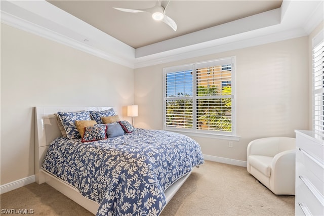 bedroom featuring ceiling fan, ornamental molding, a tray ceiling, and light carpet