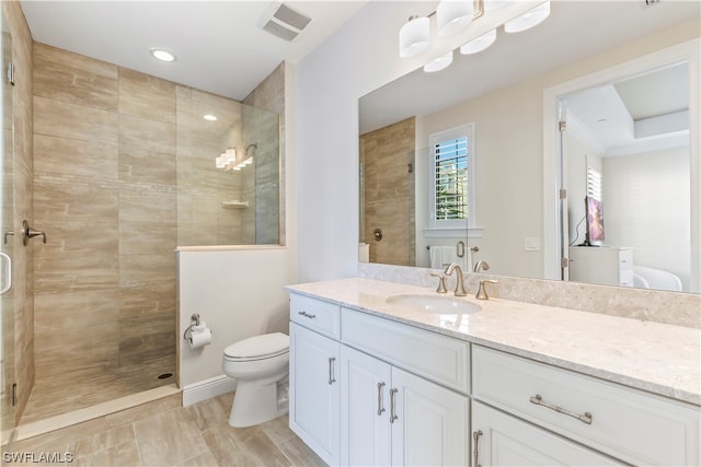 bathroom featuring vanity, tiled shower, and toilet