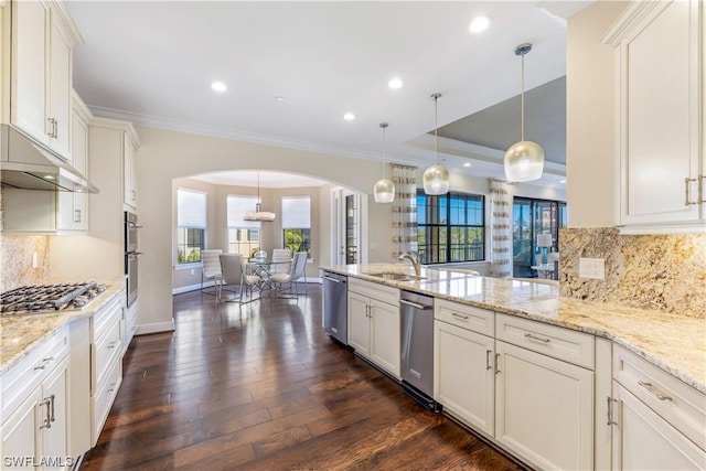 kitchen with appliances with stainless steel finishes, dark hardwood / wood-style flooring, hanging light fixtures, ornamental molding, and light stone countertops