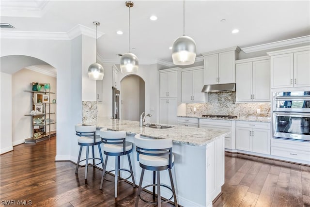 kitchen with white cabinetry, decorative light fixtures, appliances with stainless steel finishes, kitchen peninsula, and light stone countertops