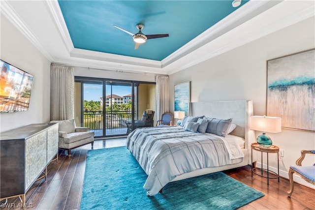 bedroom with a raised ceiling, crown molding, hardwood / wood-style flooring, and access to exterior