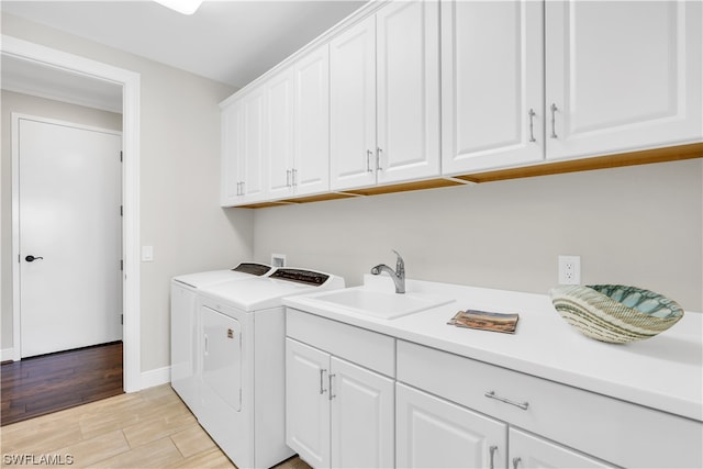 washroom with cabinets, sink, washing machine and clothes dryer, and light hardwood / wood-style flooring