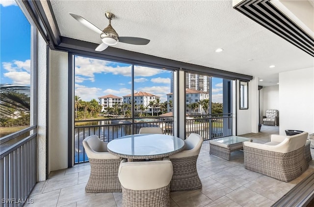 sunroom / solarium featuring a water view, ceiling fan, and a wealth of natural light