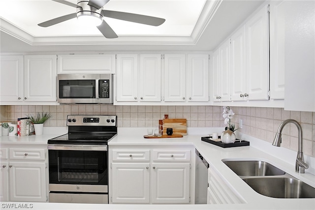 kitchen featuring appliances with stainless steel finishes, tasteful backsplash, a raised ceiling, sink, and white cabinetry