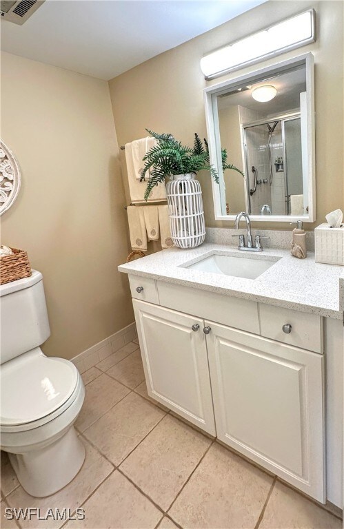 bathroom with tile patterned flooring, vanity, toilet, and an enclosed shower