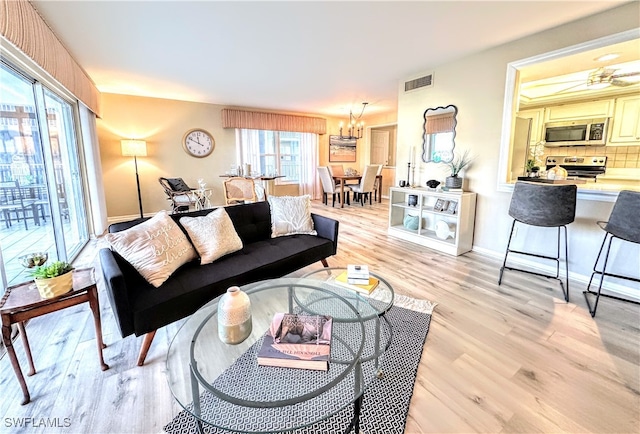 living room featuring a chandelier, light hardwood / wood-style flooring, and plenty of natural light