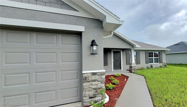 view of exterior entry with a garage and a lawn