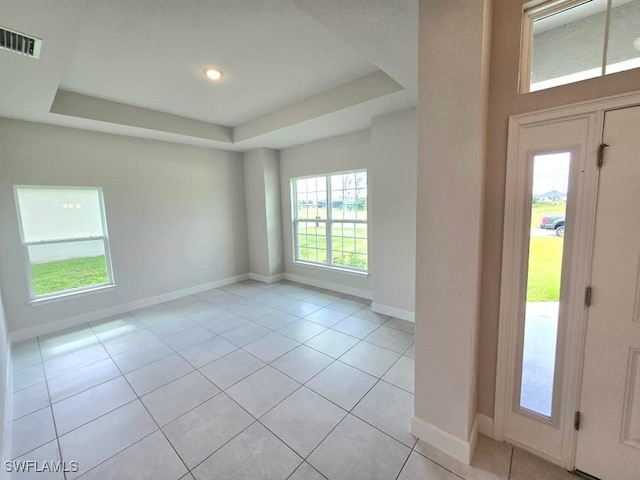 entryway with light tile patterned floors and a tray ceiling