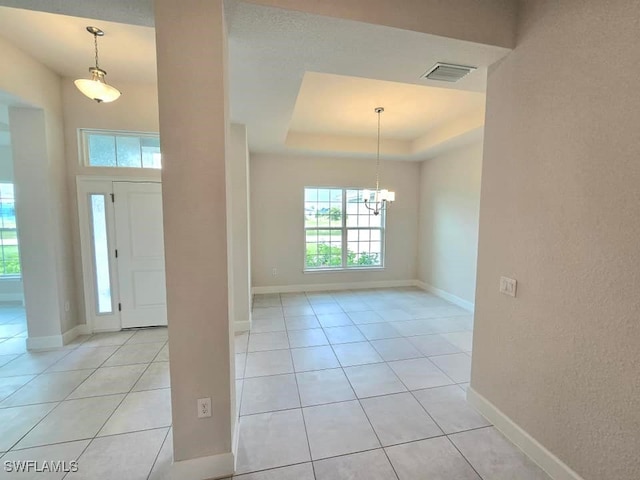 foyer entrance featuring a chandelier, a tray ceiling, and light tile patterned floors