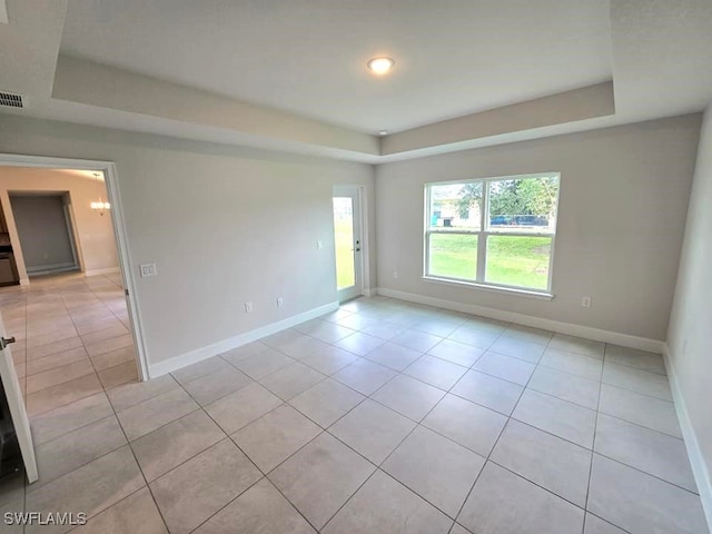 tiled spare room featuring a tray ceiling