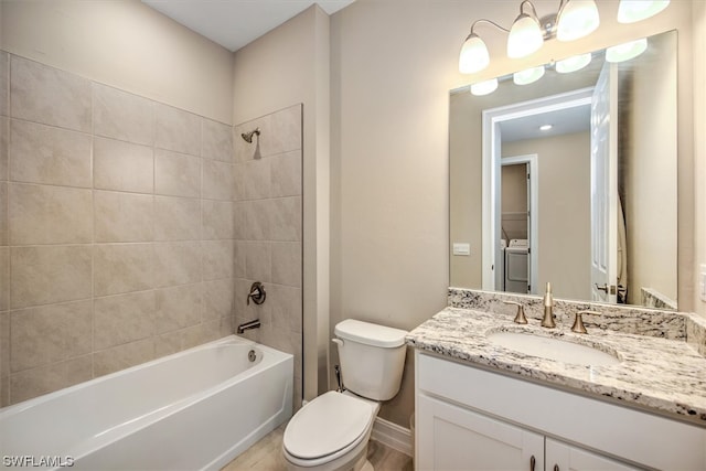 full bathroom with tiled shower / bath combo, toilet, vanity, and washer / dryer