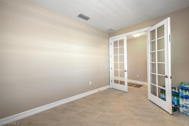 tiled spare room featuring french doors