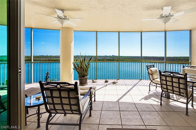 sunroom / solarium with a water view and ceiling fan