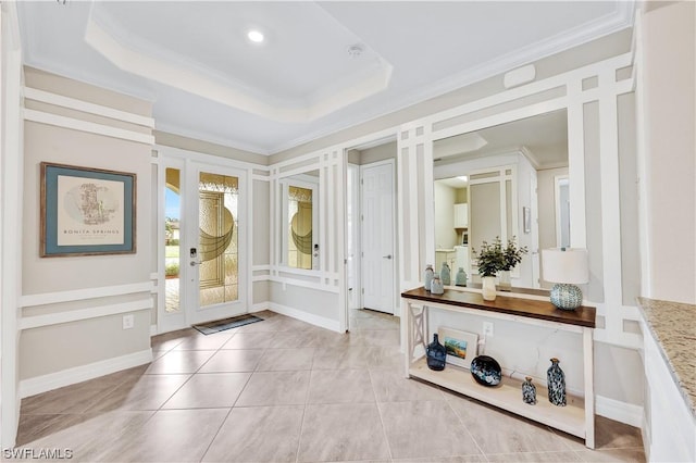 tiled foyer featuring a raised ceiling and crown molding