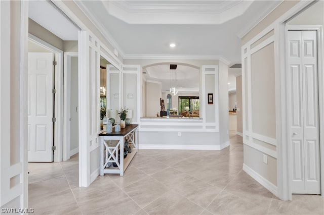 corridor with a tray ceiling and ornamental molding