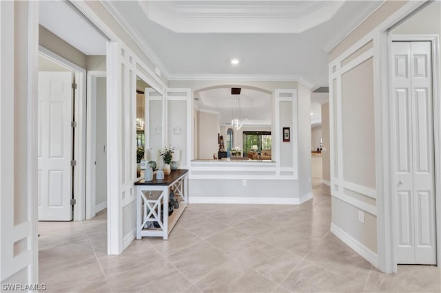 corridor featuring ornamental molding, a raised ceiling, and light tile patterned floors